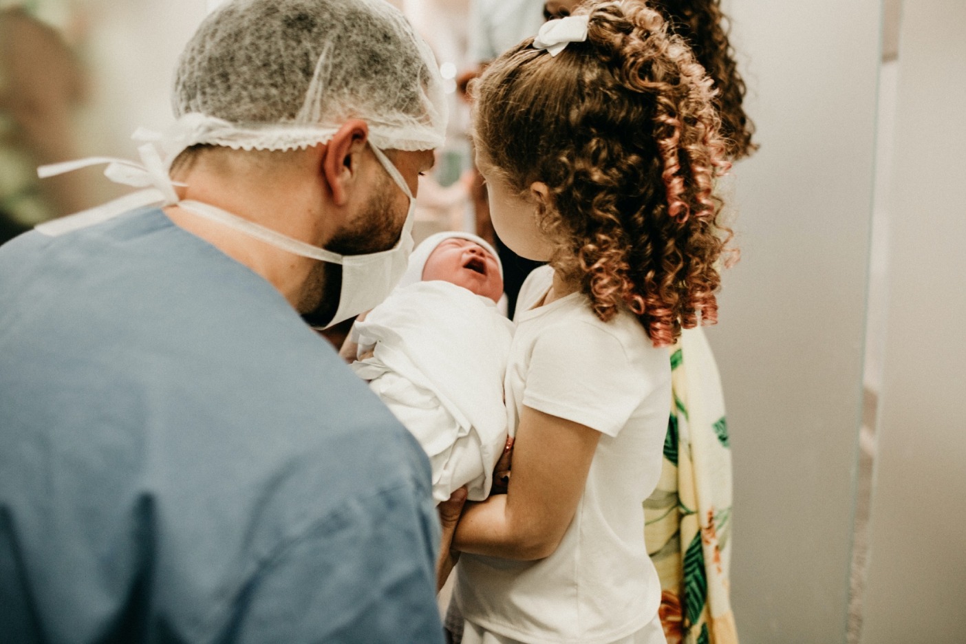 doctor handing newly born baby to sister